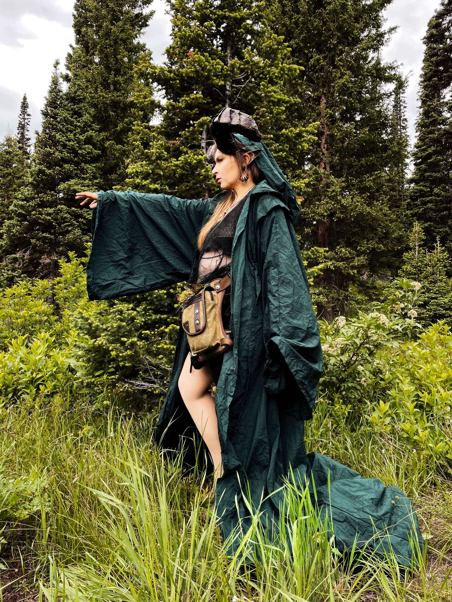 model wearing green robe and horns in forest