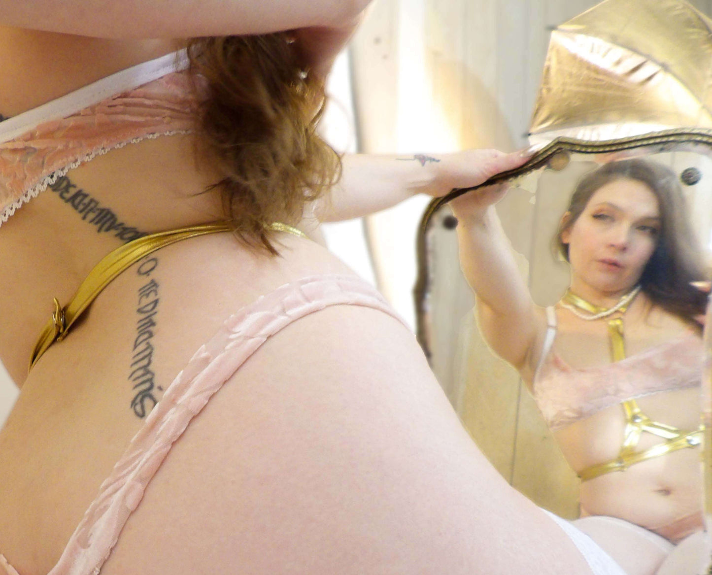 woman admiring gold harness lingerie in mirror 