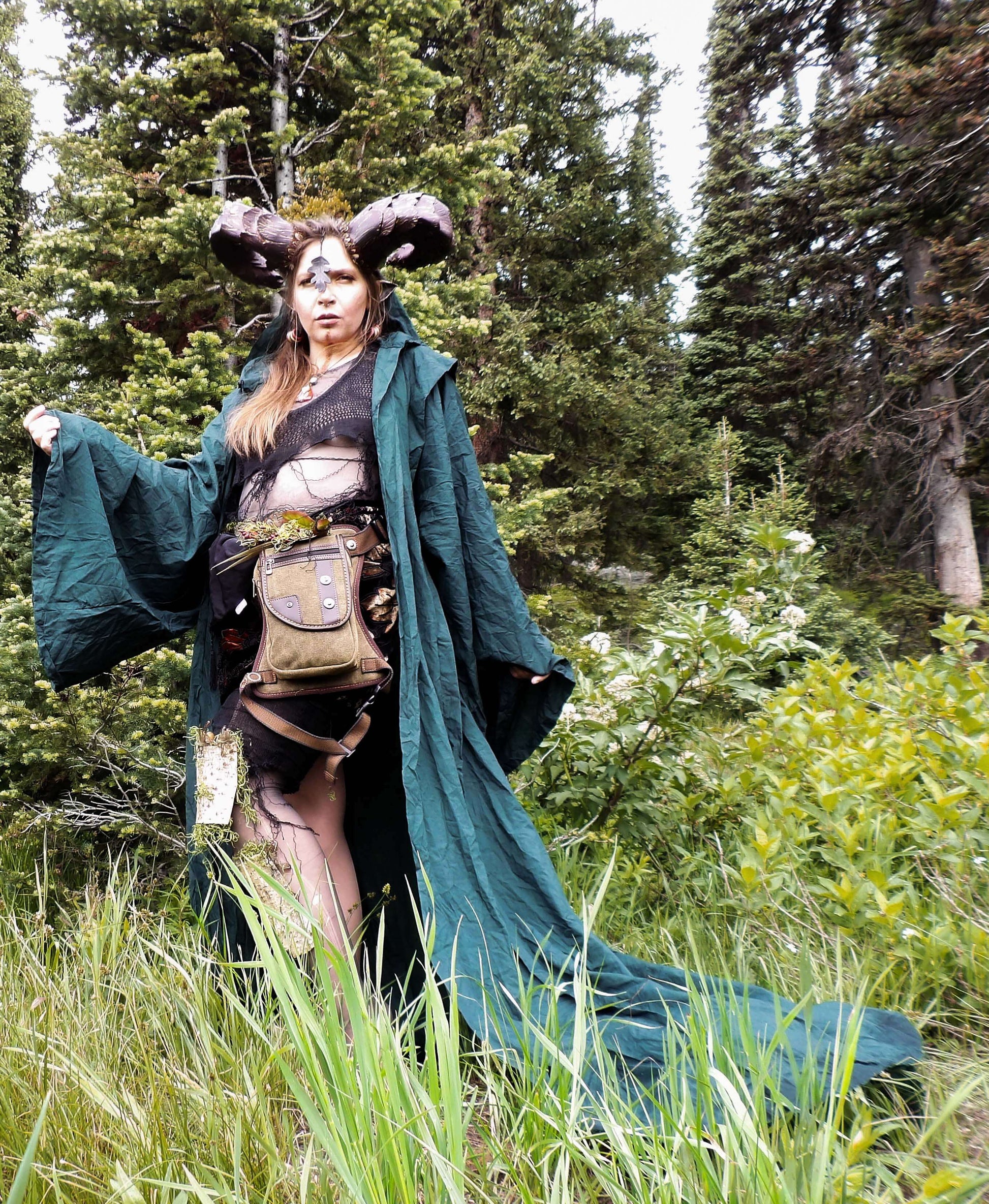 model with horns in forest wearing green 
